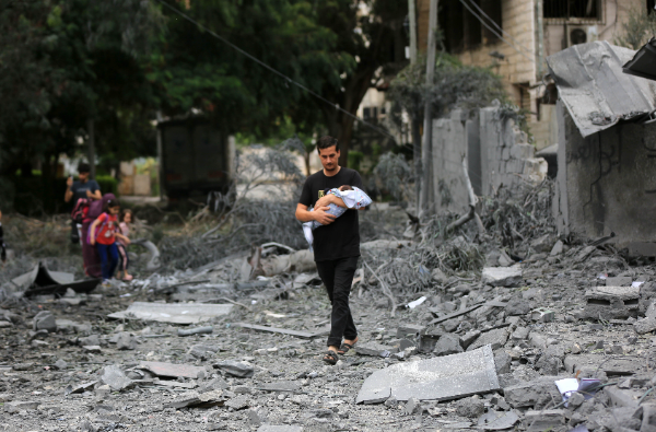 Un padre con un bebe en brazos camina sobre los escombros dejados por los bombardeos. Foto, Ashraf Amra / Gaza. 13 de octubre 2023.