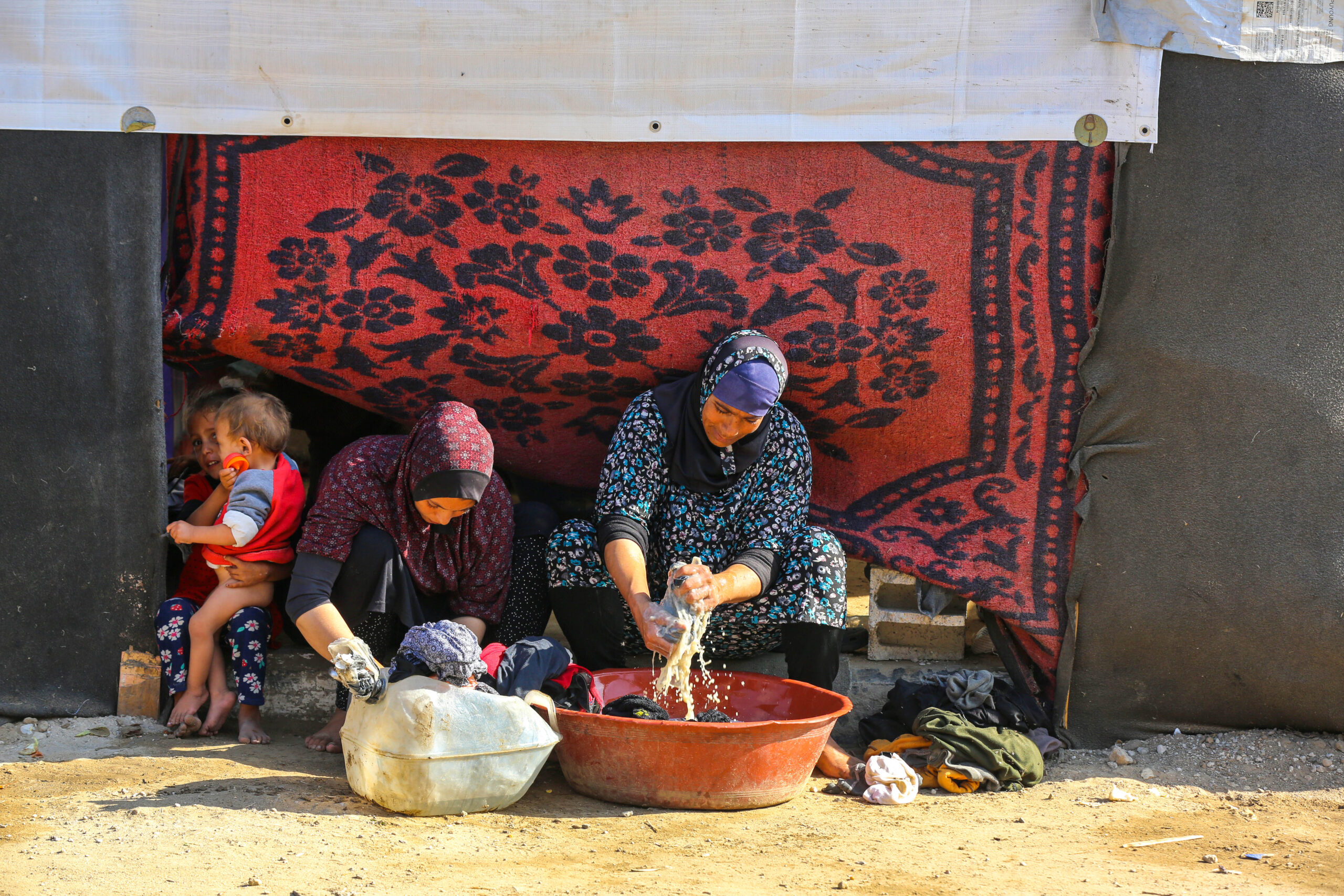 Mujeres desplazadas lavando ropa en refugio improvisado