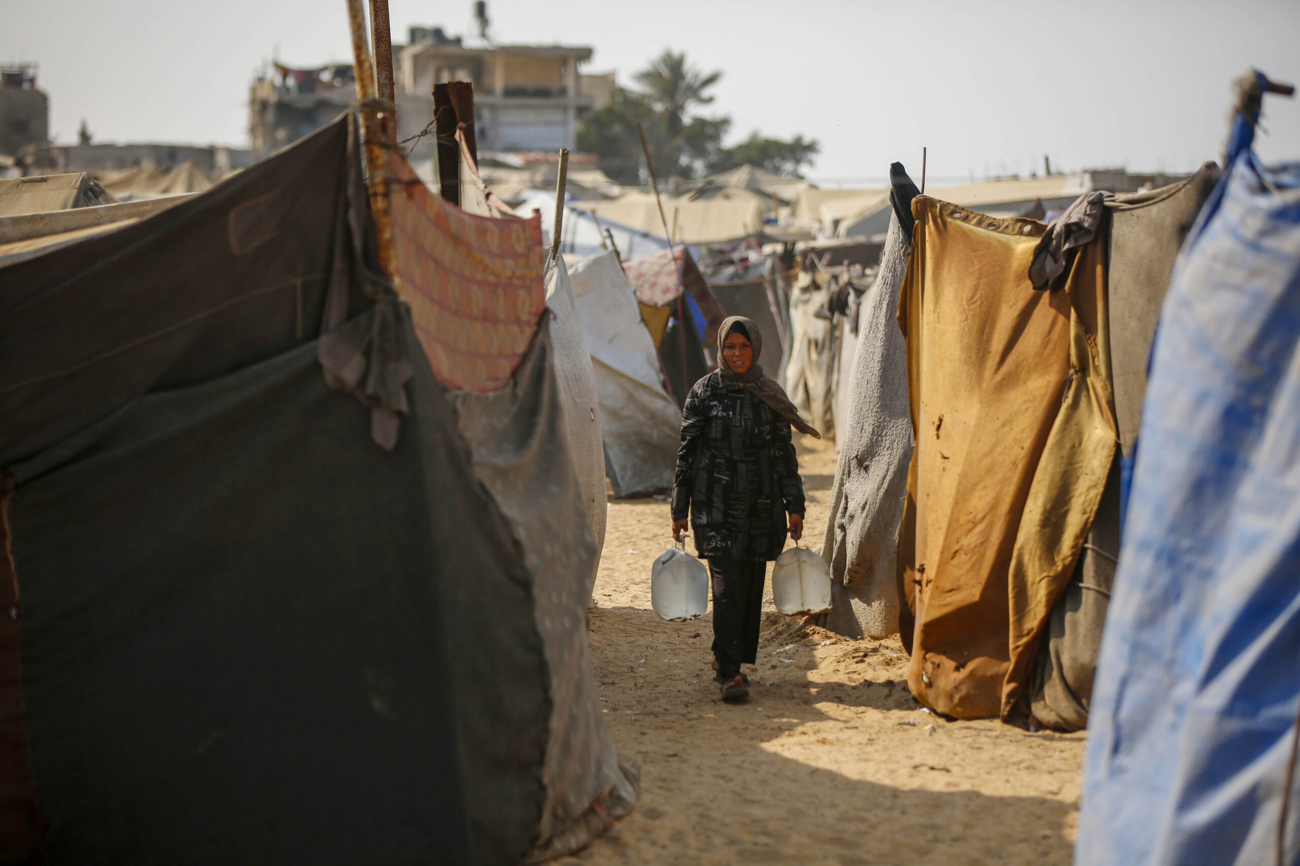 Mujer desplazada con bidones de agua