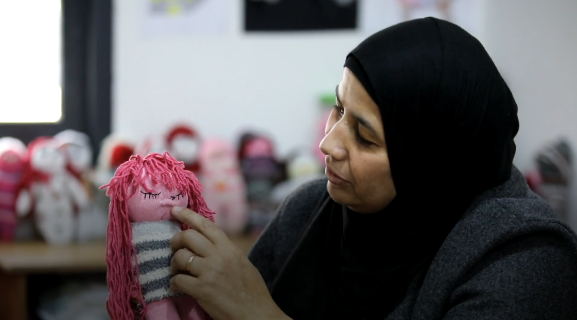 Una mujer palestina sujeta una muñeca de trapo en la mano