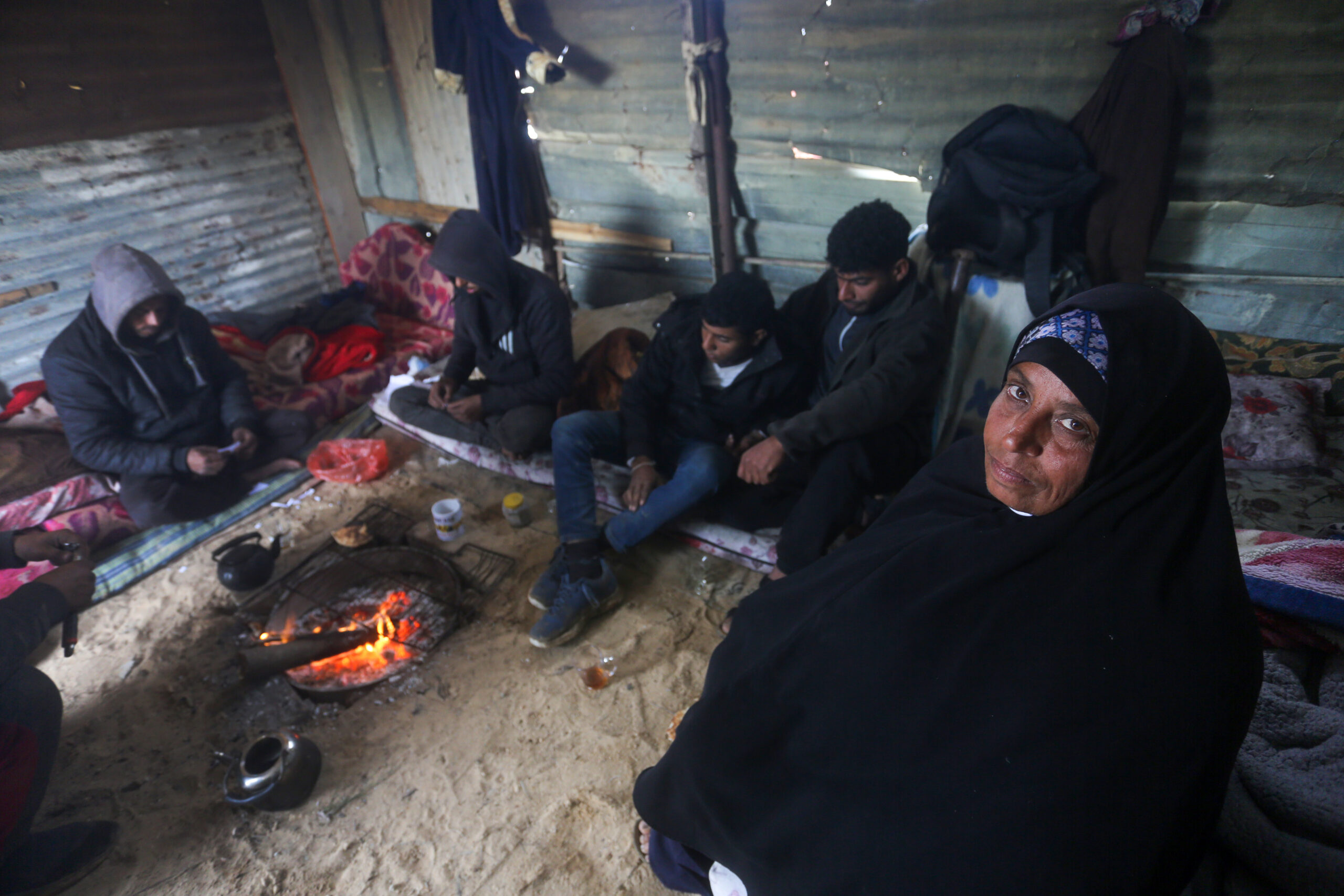 Mujer palestina junto a su familia, desplazada en una precaria tienda de campaña en Gaza