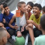 Rateb sonríe junto a sus amigos en Gaza mientras lleva una prótesis en su pierna amputada.